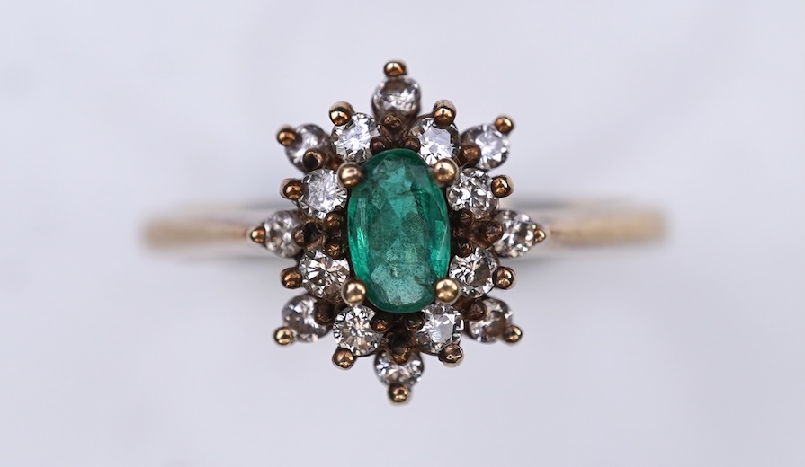An emerald and diamond cluster ring